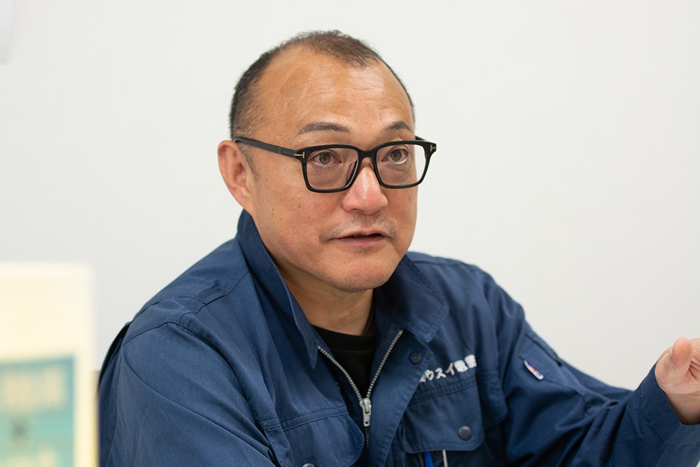 青い作業服に眼鏡をかけた男性